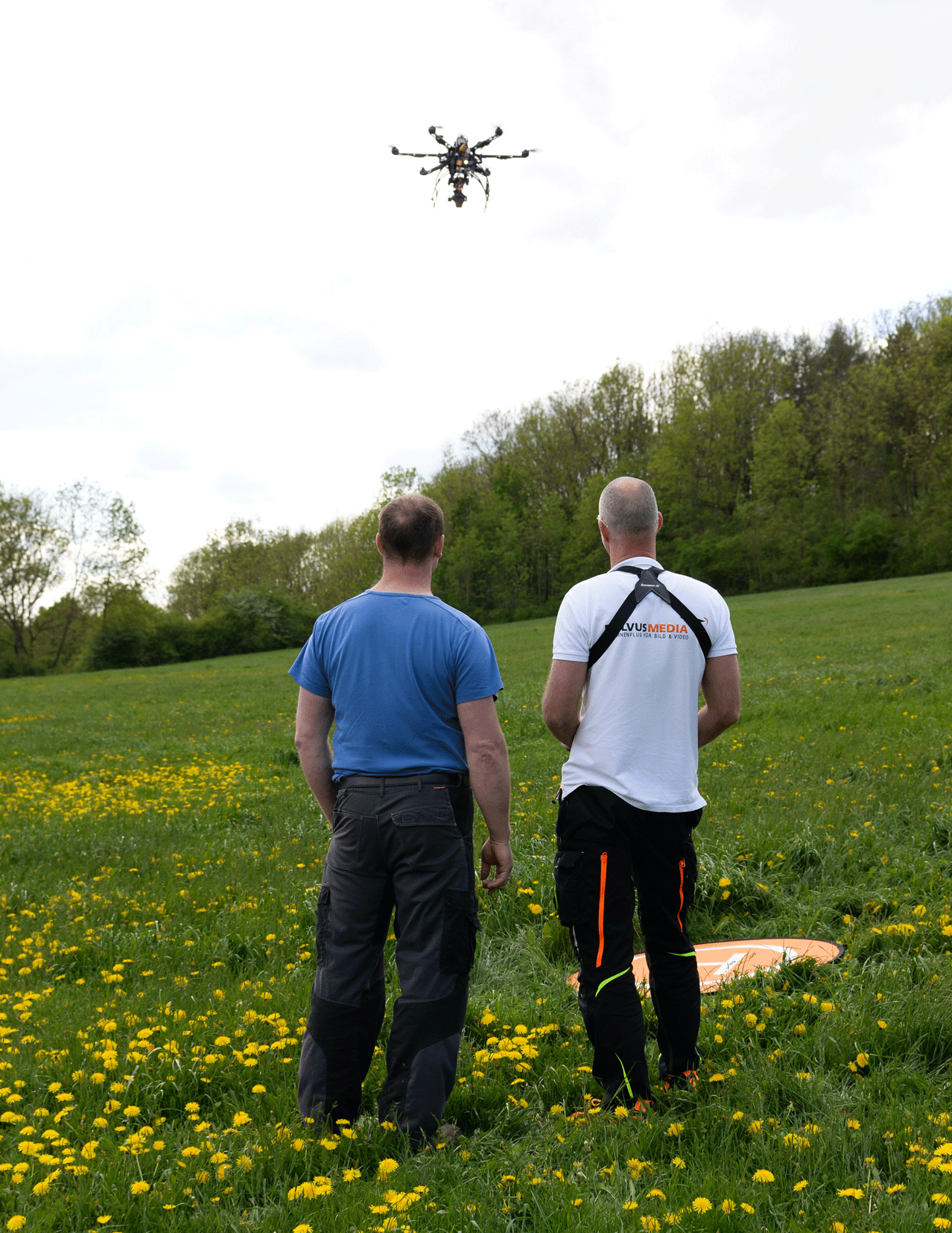 Zwei Landwirte lassen eine Drohne über Grünland fliegen. Klick führt zu Großansicht im neuen Fenster.