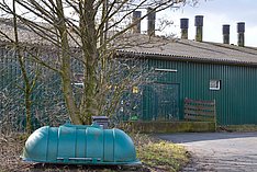 Schweinestall mit Abluftschächten. Davor ein Kadaverbehälter. Klick führt zu Großansicht im neuen Fenster.