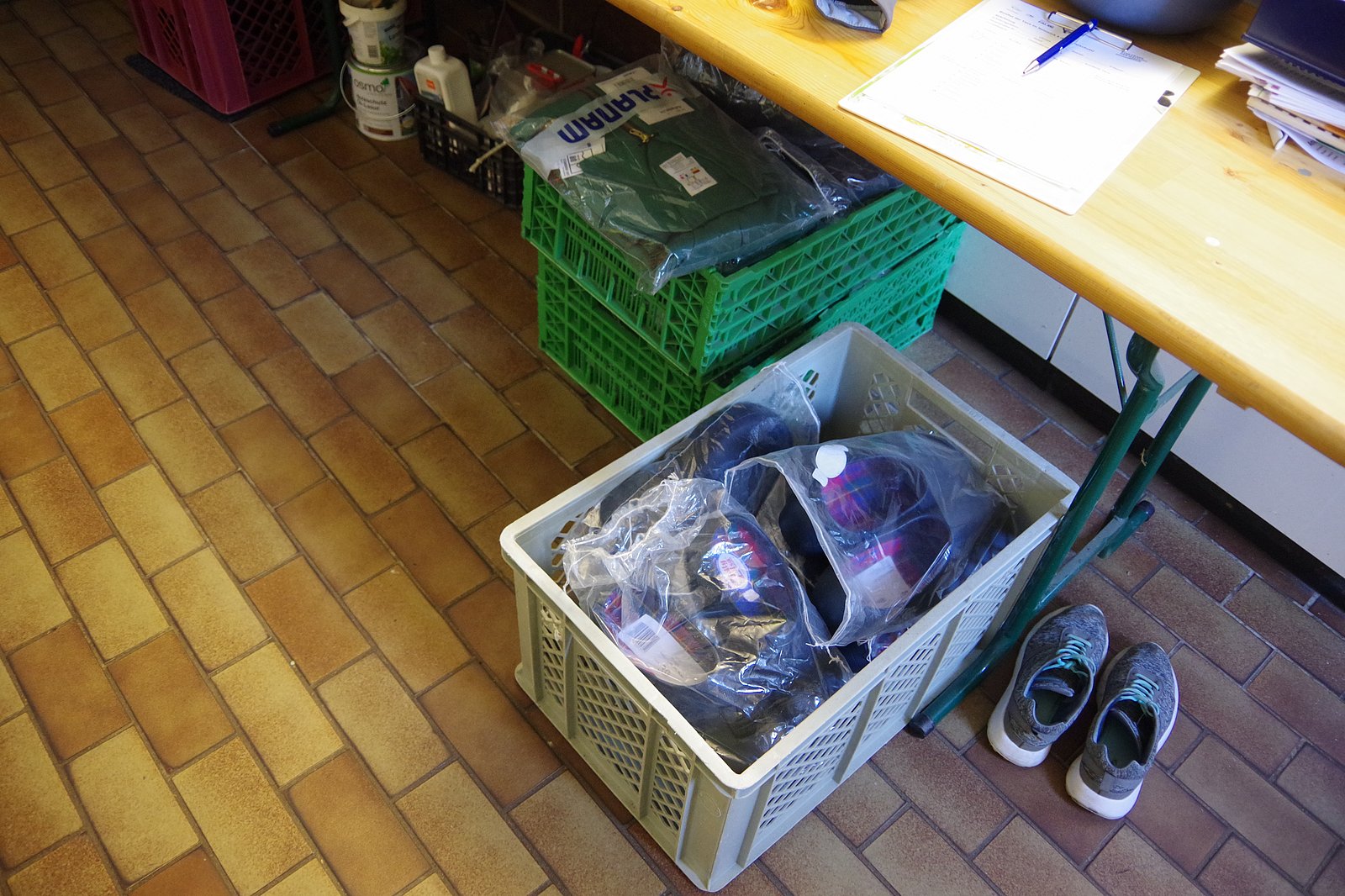 Kisten mit Schutzkleidung und Schuhen stehen auf dem Boden. Klick führt zu Großansicht in neuem Fenster.