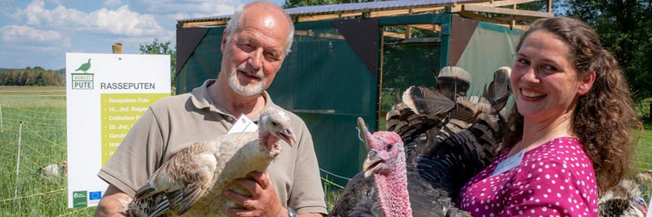 Zwei Personen mit einer Pute auf dem Arm. 