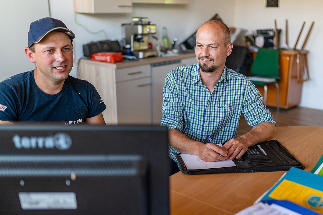 Landwirt mit Berater vor einem PC. Klick führt zu Großansicht im neuen Fenster.