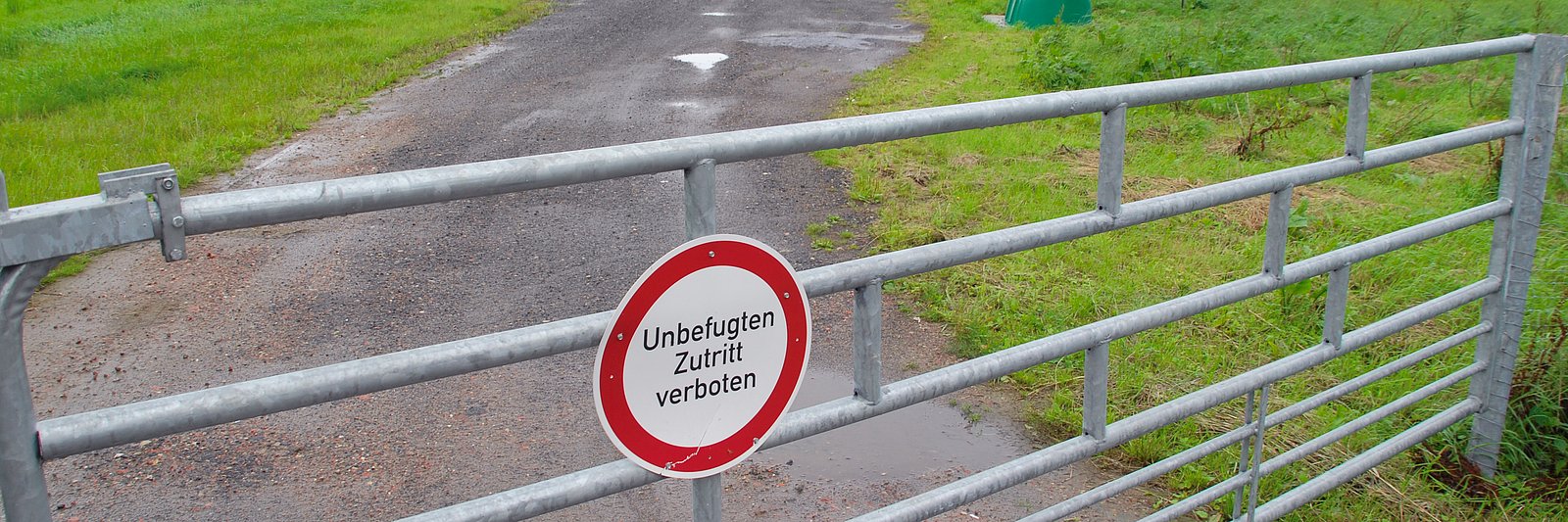 Stallanlage mit Biogas-Fermenter eines Schweinebetriebs, im Vordergrund ein Schild "Unbefugten Zutritt verboten" und ein Zaun